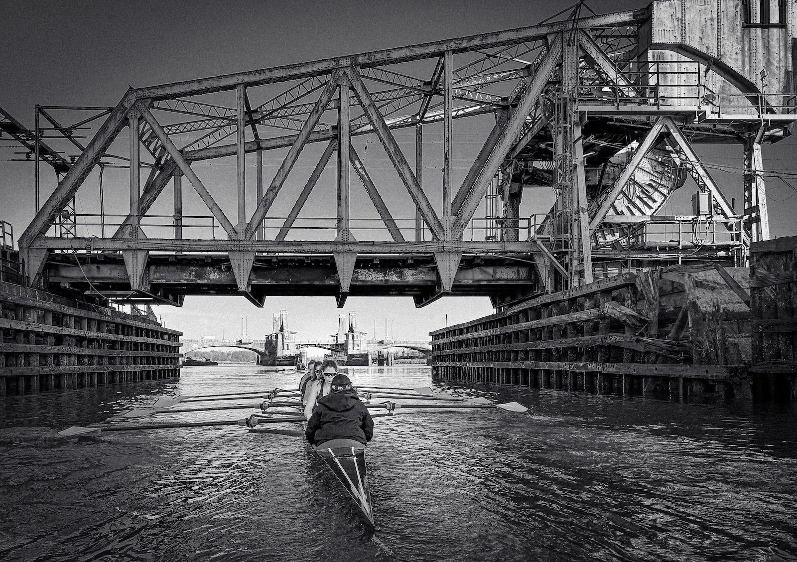 A sculler approaching the swing bridge, in black and white