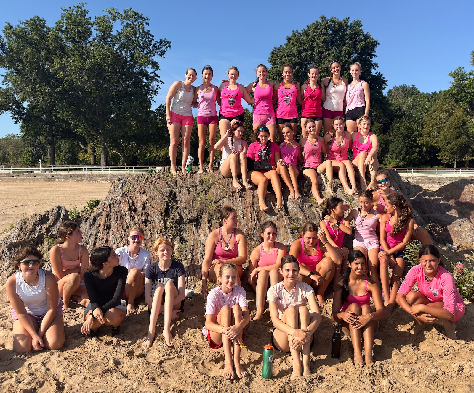 The whole squad in pink, posed on the big rock on the beach after the Summer Olympics