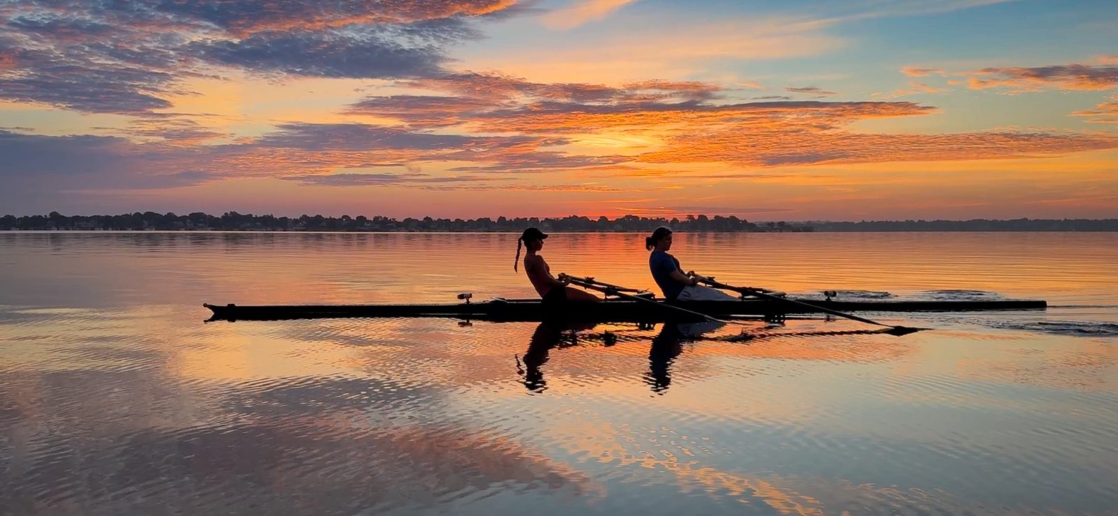 A pair on fire-colored water at sunrise