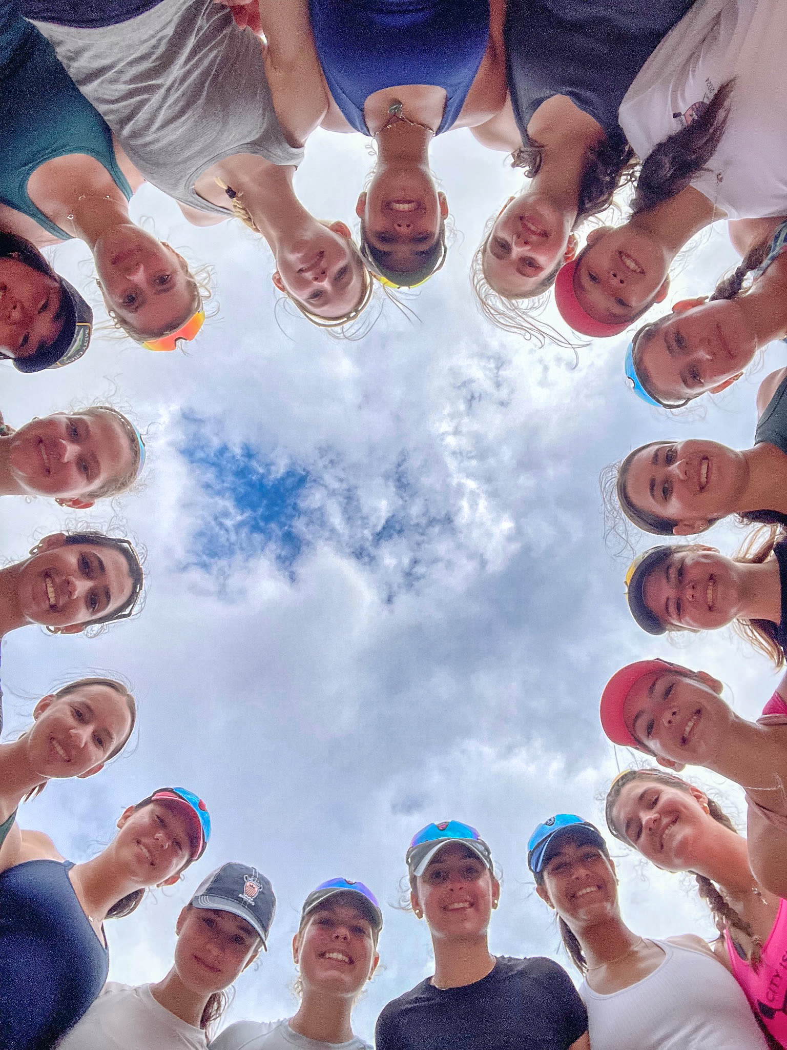 The whole team in a circle, faces in, looking up at the camera