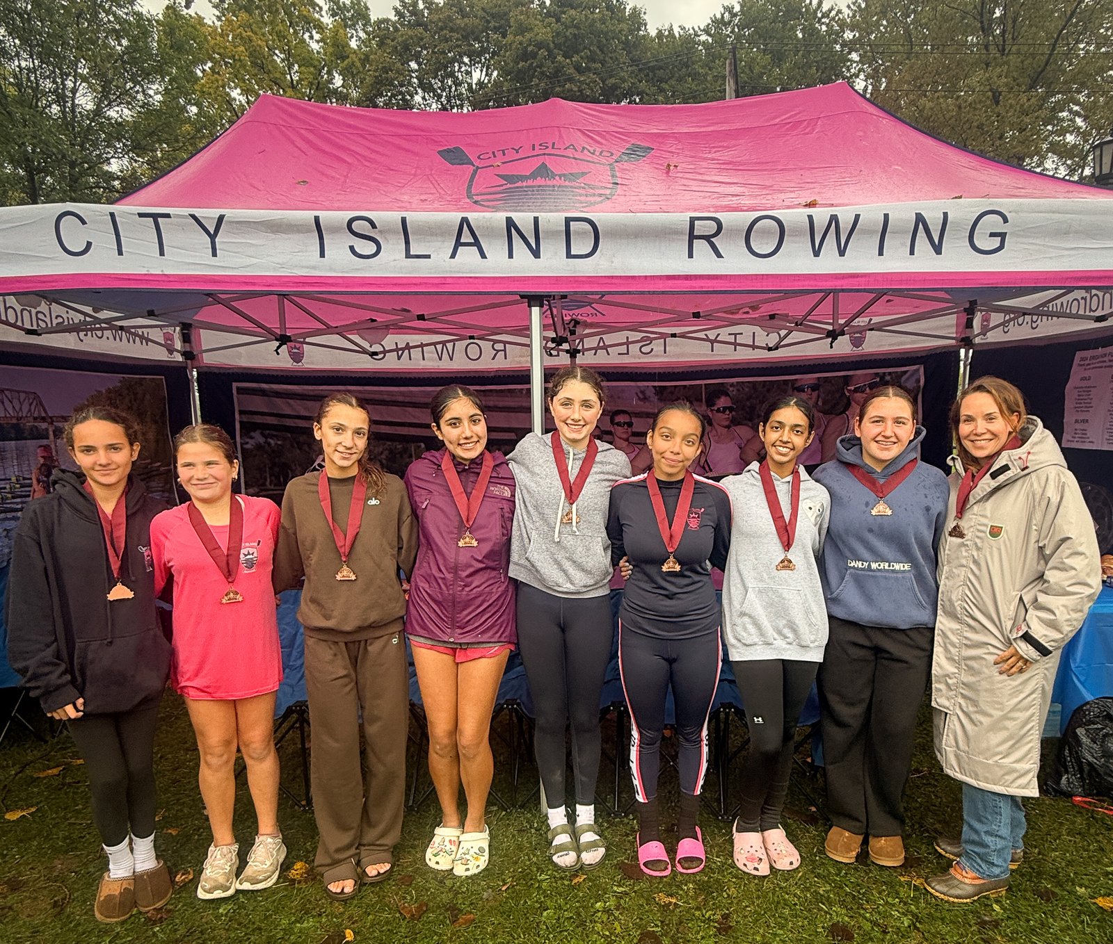 The novice eight with their bronze medals under the CIR tent