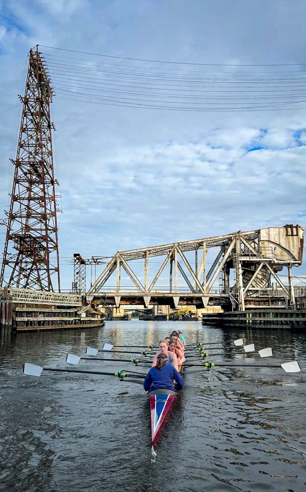 A single sculler under the railroad bridge