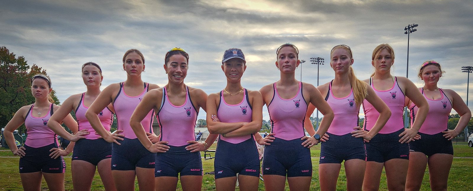 The first varsity eight, arms on hips, lined up on the grass