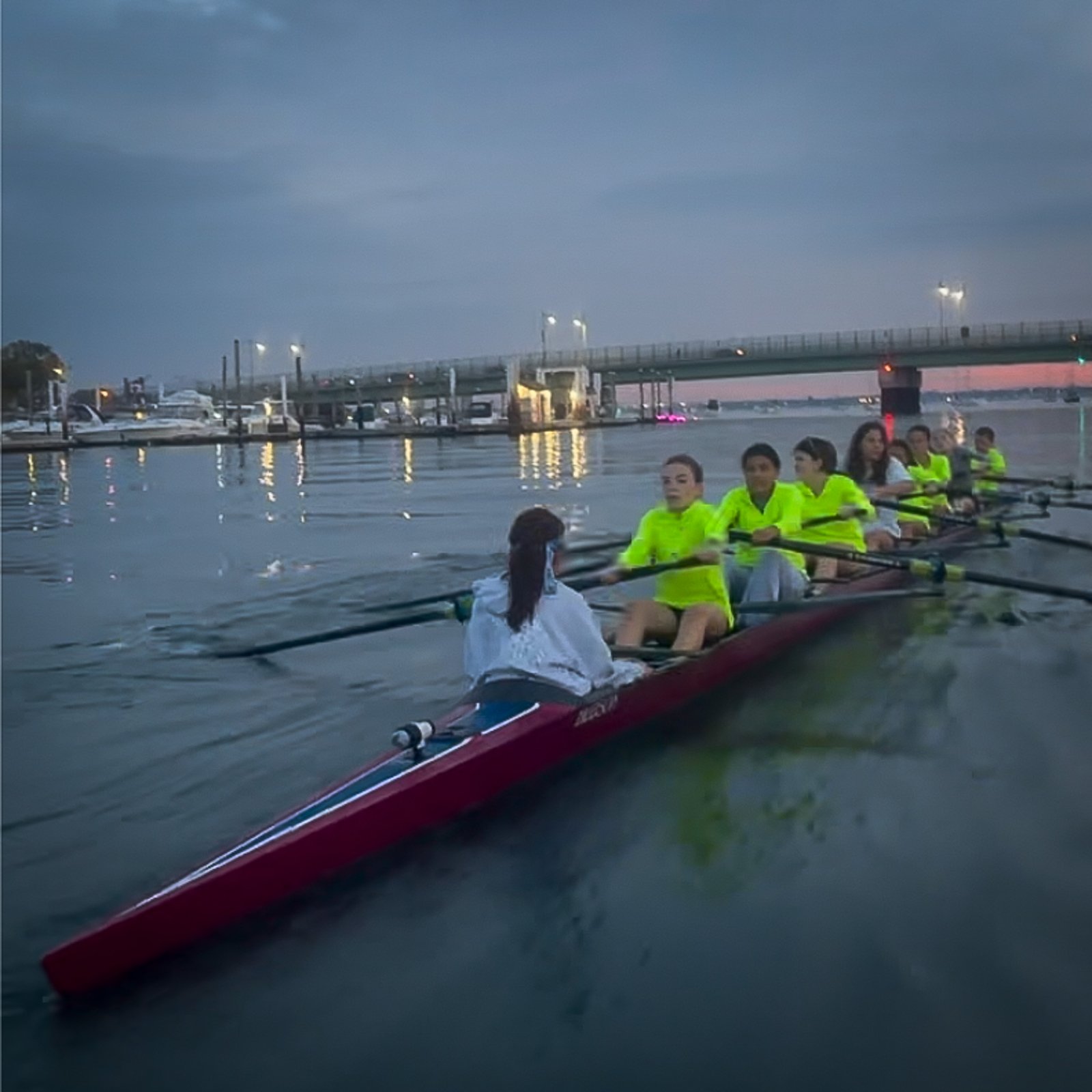 An eight in hi-vis at dusk under the bridge
