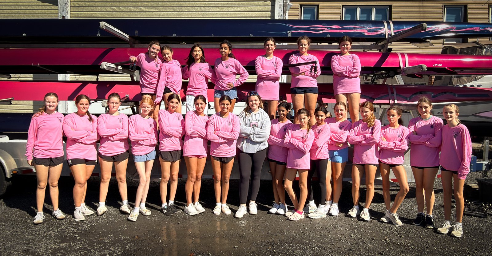 The U16 squad in pink, lined up in front of the boats